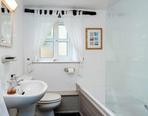 La salle de bains blanche est pourvue d'un lavabo et de toilettes. dans l'établissement The Granary, à Saint Minver
