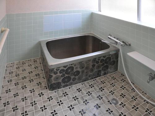 a bath tub in a bathroom with a tiled floor at carafuru Japanese Old House in Sado