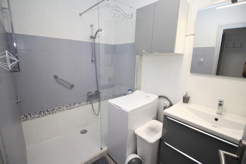 une salle de bain blanche avec une douche et un lavabo dans l'établissement QUAI12- Appartement T2 vue Marina, à Canet
