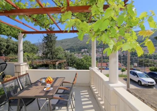 patio z drewnianym stołem i krzesłami na balkonie w obiekcie Dubrovnik Hill Apartments w Dubrowniku