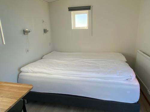a bed in a small room with a small window at Uxahryggur in Hvolsvöllur