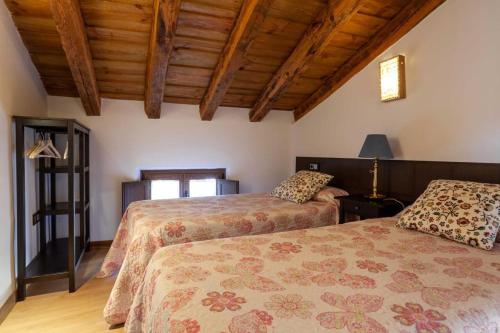 two beds in a room with wooden ceilings at Apartamentos Top Medieval in Sigüenza