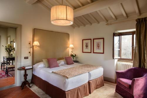 a bedroom with a large bed and a purple chair at Il Borro Relais & Châteaux in San Giustino Valdarno
