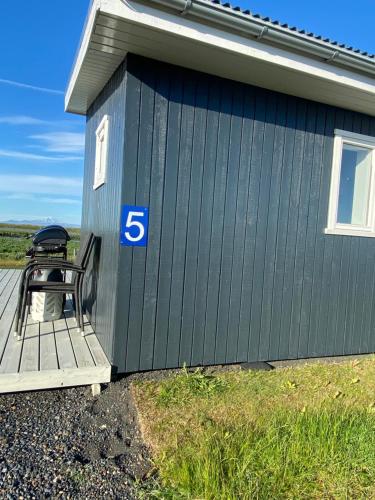 a blue building with a bench on a deck at Uxahryggur in Hvolsvöllur