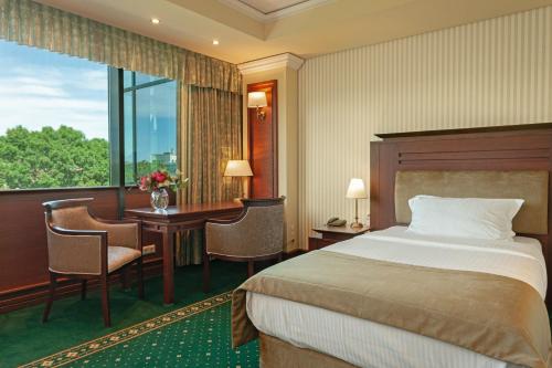 a hotel room with a bed and a desk and a window at Grand Hotel Sofia in Sofia