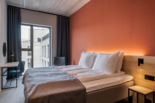 a bedroom with a large bed with an orange wall at Citybox Antwerp in Antwerp