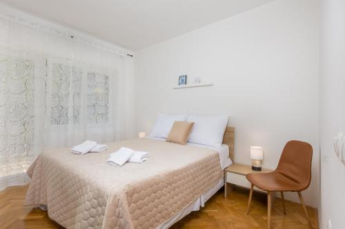 a white bedroom with a bed and a chair at Apartment Ana in Vantačići