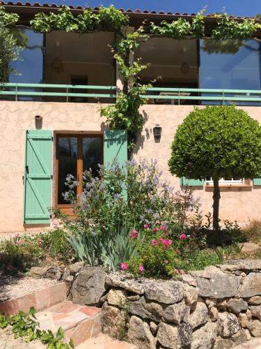 a house with a green door and flowers at Les Bosquets in Lorgues