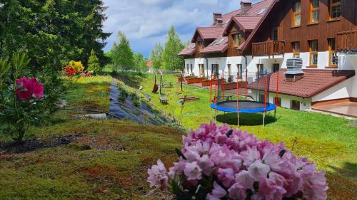 um quintal com flores cor-de-rosa e um parque infantil em Hotel Rezydencja AS & Spa-Najwyżej w Karpaczu em Karpacz