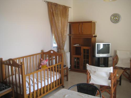 a living room with a crib and a tv at Dimitra Apartments Zakros Village in Káto Zákros