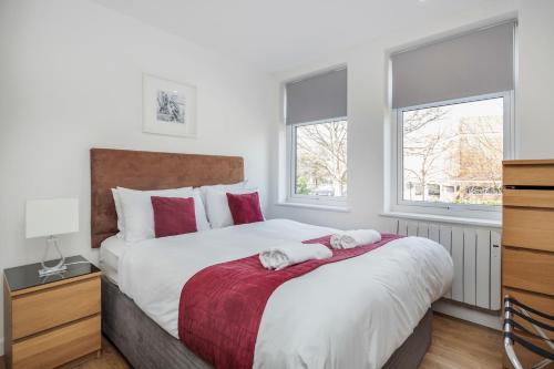 a bedroom with a large bed and two windows at Roomspace Serviced Apartments - Swan House in Leatherhead