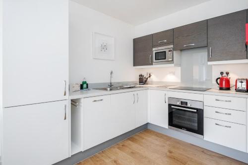 eine weiße Küche mit weißen Schränken und Geräten in der Unterkunft Roomspace Serviced Apartments - Swan House in Leatherhead