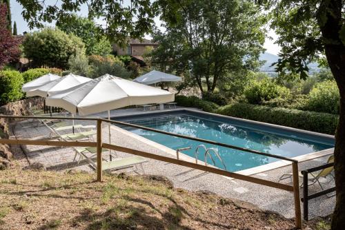 a swimming pool with two umbrellas and a swimming poolvisor at Le Terre Di Isa in Magione