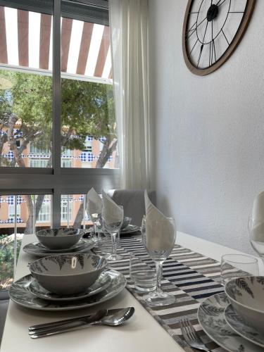 una mesa con platos y gafas y un reloj en la pared en Appartement ‘’Los Pinos’’ 50m de la plage en Grao de Castellón
