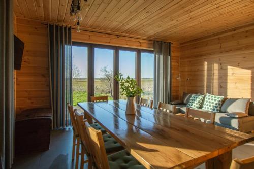 a dining room with a wooden table and a couch at Domek w Biebrzańskim Eldorado in Stare Dolistowo