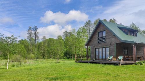 ein Holzhaus mit zwei Stühlen auf einem Feld in der Unterkunft Domek w Biebrzańskim Eldorado in Dolistowo Stare