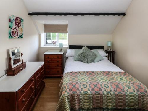 a bedroom with a bed and a dresser and a window at Y Cartws in Llandysul