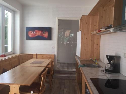 eine Küche mit einem Holztisch und einem Augengemälde in der Unterkunft Gästehaus in der Friedensfabrik in Wanfried