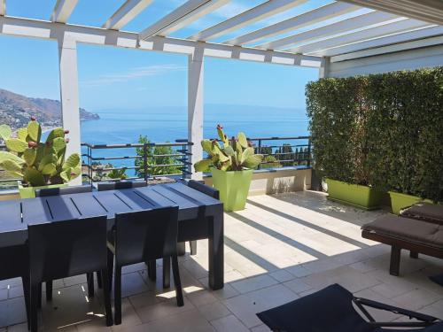 een patio met een tafel en uitzicht op de oceaan bij Taormina Romantic Apartment by Taormina Holidays in Taormina