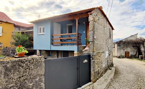 une maison avec une porte bleue et un mur en pierre dans l'établissement Casa Rural d 'Avó - sossego do campo - 5 adultos, à Alhais
