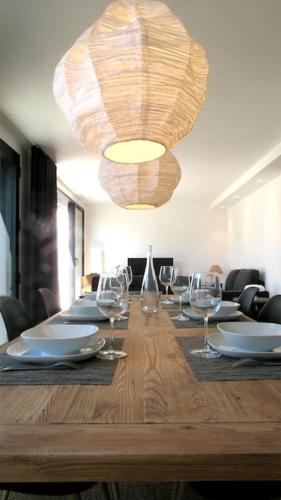une longue table en bois avec des verres à vin et un lustre dans l'établissement Maison de vacances Lesconil à 500 m de la plage, à Plobannalec-Lesconil