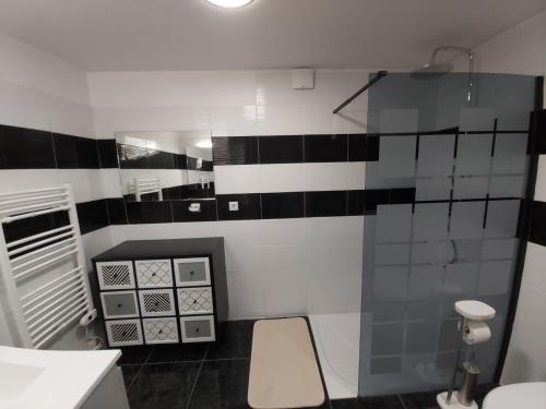 La salle de bains est pourvue de carrelage noir et blanc sur le mur. dans l'établissement Le Mas d'Evlie, à Aubin
