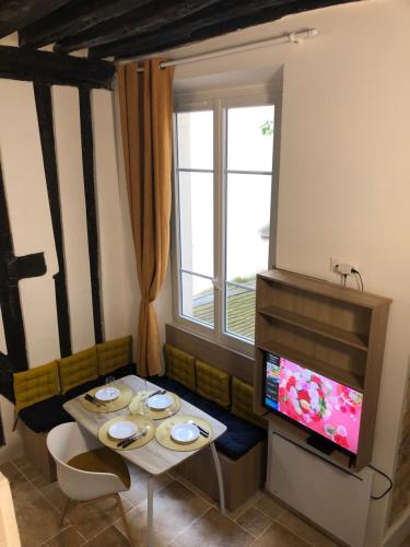 ein Wohnzimmer mit einem Tisch und einem TV in der Unterkunft A 2 Pas de Panthéon Quartiers Latins in Paris