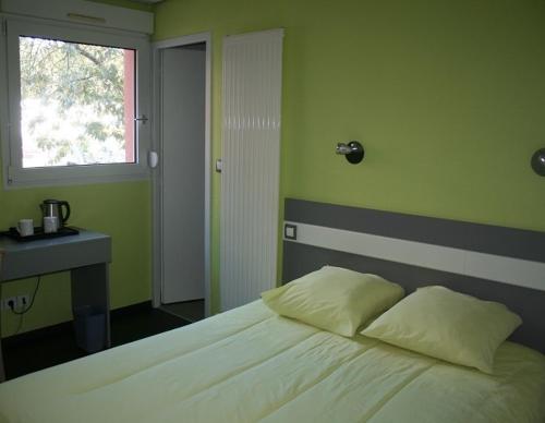 une chambre avec un lit, un bureau et une fenêtre dans l'établissement Kyriad Direct Lure, à Lure