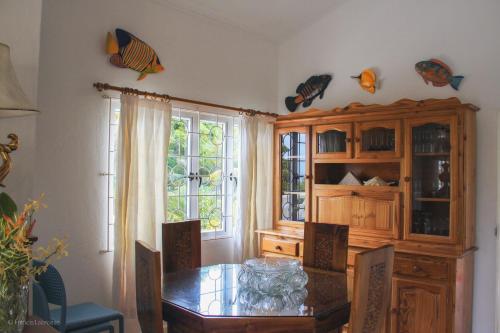 a dining room with a table and a wooden cabinet at Residence Monte-Cristo in Anse Boileau