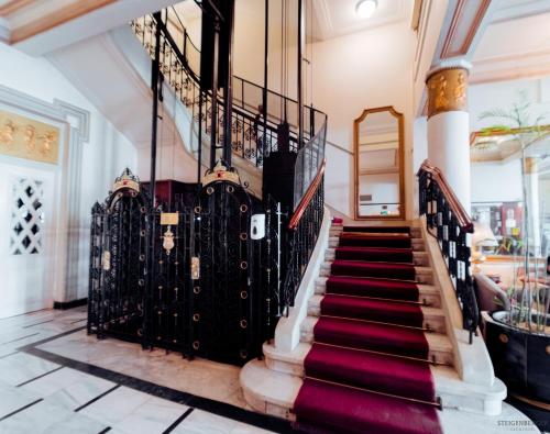 a staircase in a house with a red carpet at Steigenberger Cecil Hotel Alexandria in Alexandria
