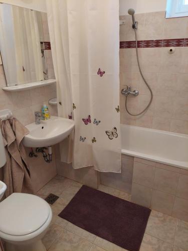 uma casa de banho com um WC, um chuveiro e um lavatório. em Evelin vendégház em Bogács