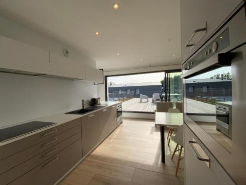 une cuisine avec des placards blancs et une grande fenêtre dans l'établissement ARRADON 400m bourg, plages et port, à Arradon