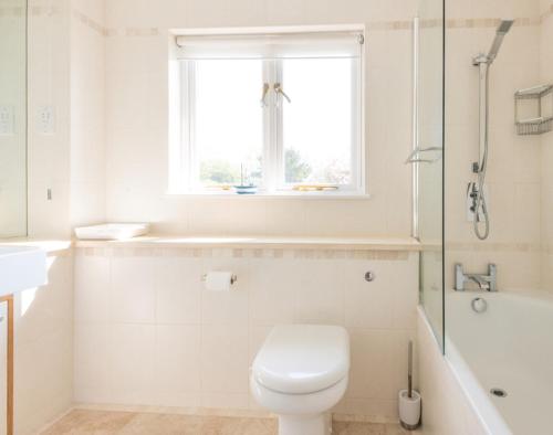 a white bathroom with a toilet and a window at Ragleighs in Polzeath