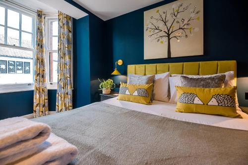 a bedroom with blue walls and a bed with yellow pillows at The Picture House, Aldeburgh in Aldeburgh