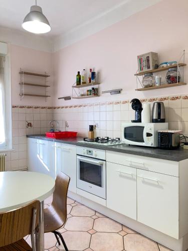 une cuisine avec des armoires blanches et une table à l'intérieur dans l'établissement Le Campus Victoria II - Train Station & Isabey St - 75m2, à Nancy