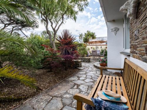 a wooden bench sitting on a porch with plants at Longhouse Bungalow in Polzeath