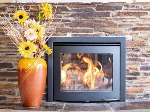 a fireplace and a vase with flowers next to a brick wall at Longhouse Bungalow in Polzeath