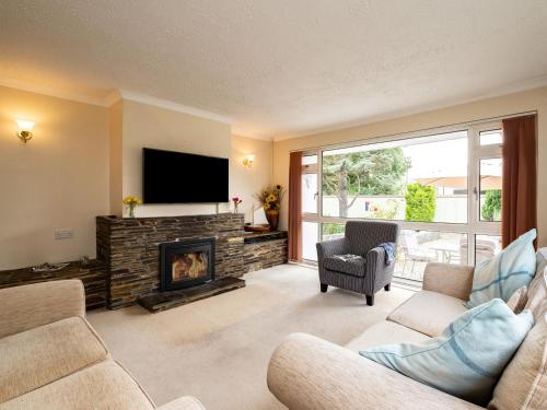 a living room with a fireplace and a flat screen tv at Longhouse Bungalow in Polzeath