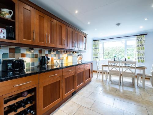 a kitchen with wooden cabinets and a dining room with a table at Longhouse Bungalow in Polzeath