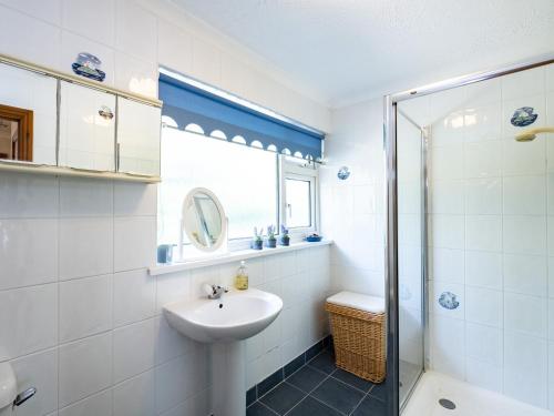 a white bathroom with a sink and a shower at Longhouse Bungalow in Polzeath