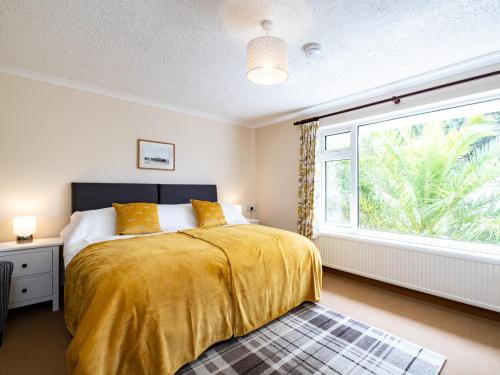 a bedroom with a bed and a large window at Longhouse Bungalow in Polzeath