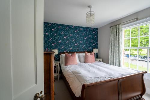 a bedroom with a bed with a blue wall at Charming renovated cottage in Hartley Wintney in Hartley Wintney