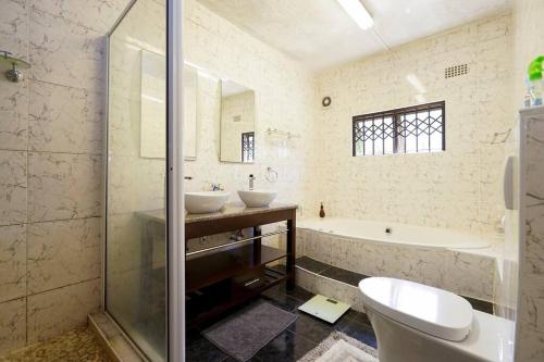 y baño con 2 lavabos, bañera y aseo. en Modern Luxury 3 bedroom house en Durban
