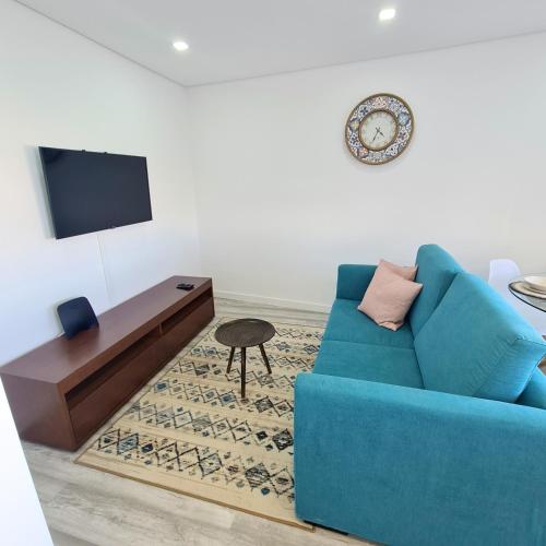 uma sala de estar com um sofá azul e uma televisão em S. Soares T3 Setúbal em Setúbal