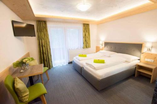 a hotel room with a large bed and a table and chairs at Haus Alblitt in Kappl