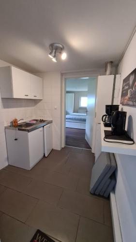 una cocina con armarios blancos y una habitación con cama en Monteurzimmer Senzig, en Königs Wusterhausen