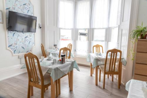 a dining room with tables and chairs and windows at Rosita Guest House in Weston-super-Mare