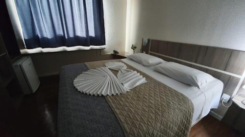 una camera da letto con un letto con una coperta e cuscini di LH Plaza Hotel a Chapecó