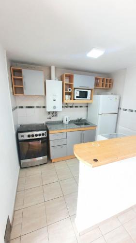 a kitchen with white appliances and a wooden table at Zafiro 2 dormitorios Céntrico in Santa Fe