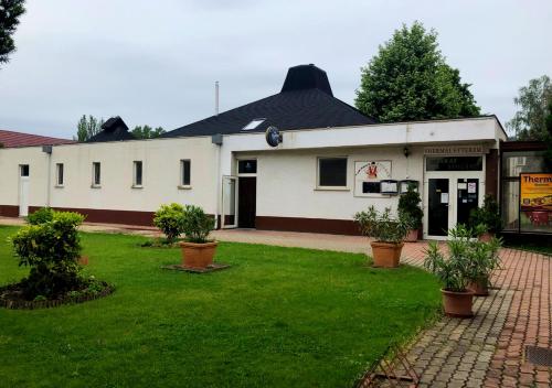 a white building with a green lawn in front of it at Hotel Imperial Gyogyszallo es Gyogyfurdo in Kiskőrös